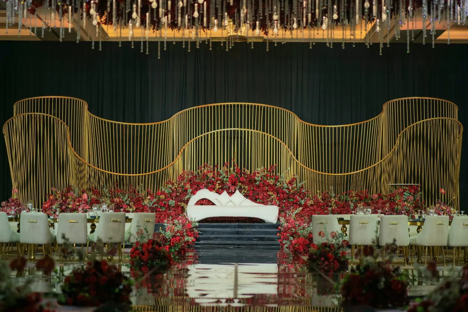 Crimson-and-gold Baraat stage with cascading florals