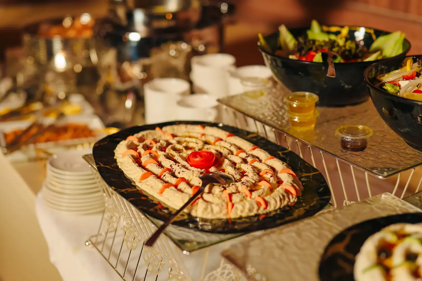 Long Arabic dining table with live Emirati food stations, dates, mezze and Arabic coffee service in the desert