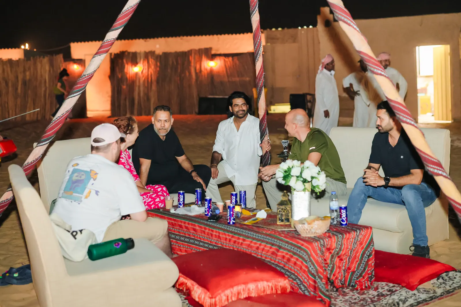 Guests seated in a lantern-lit majlis at the camp