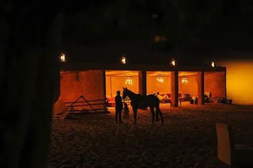 Full desert camp layout with majlis and staging at golden hour