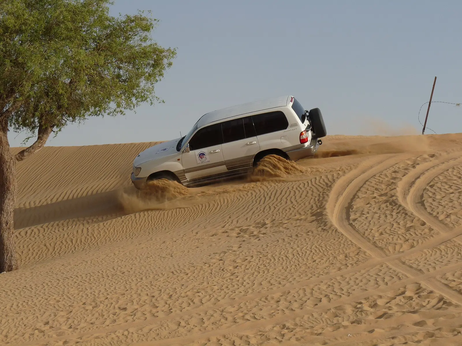 A 4x4 driving over a dune ridge in the northern emirates desert